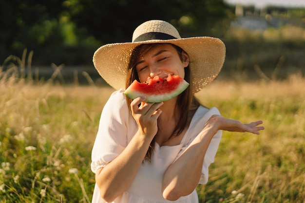 Glückliches Mädchen im Park im Freien mit erfrischender Wassermelonenfruchtfrau isst ein Stück Wassermelone