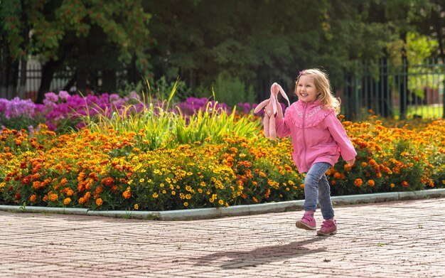 Glückliches Mädchen in Jeanshosen und einer leichten Jacke und Sportschuhen rennt durch den Park