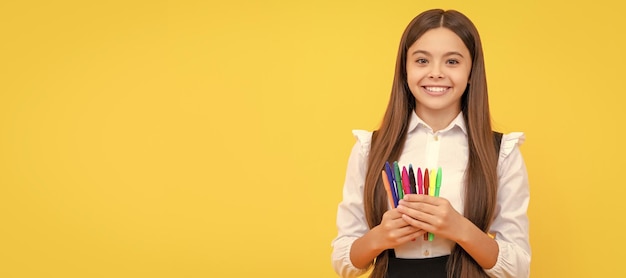 Glückliches Mädchen Kind halten Filzstifte gelber Hintergrund Schulmaterial Porträt von Schulmädchen Student Studio Banner Header Schulkind Gesicht Copyspace