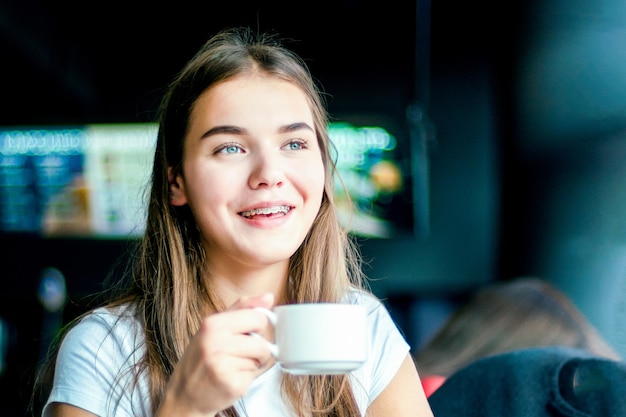 Glückliches Mädchen lächelt und trinkt Kaffee im Café