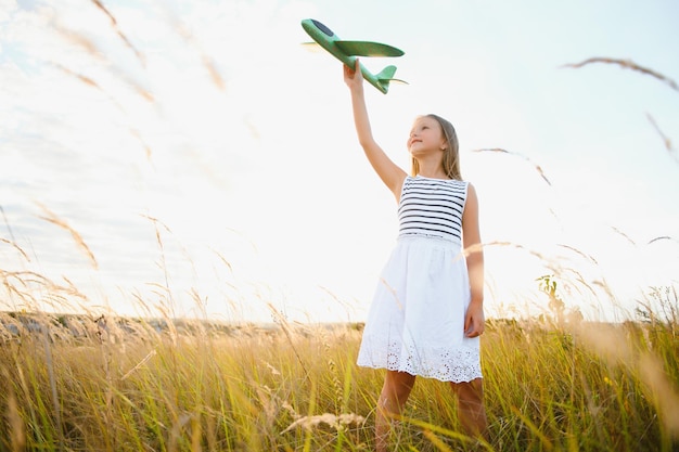 Glückliches Mädchen läuft mit einem Spielzeugflugzeug auf einem Feld im Abendlicht Kinder spielen Spielzeugflugzeug Teenager träumen vom Fliegen und werden Pilotin Mädchen will Pilotin und Astronautin werden Zeitlupe