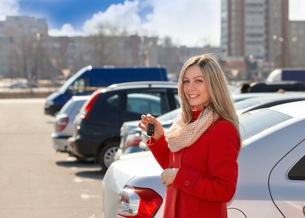 Glückliches Mädchen mit Autoschlüsseln in der Hand im Parkplatz