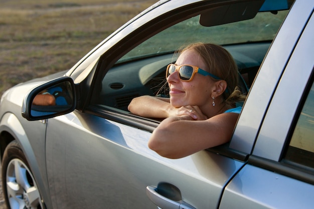 Glückliches Mädchen mit Brille schaut aus dem Auto