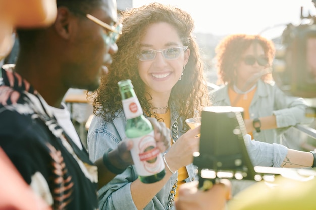 Glückliches Mädchen mit Cocktail im Gespräch mit ihrem afroamerikanischen Freund mit Bier