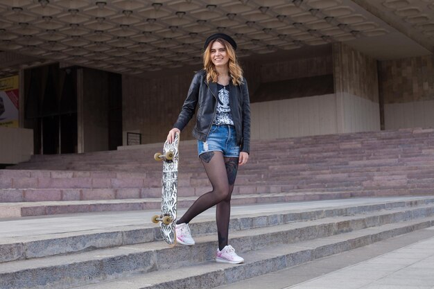 Glückliches Mädchen mit dem Skateboard, das die Treppe hinuntergeht