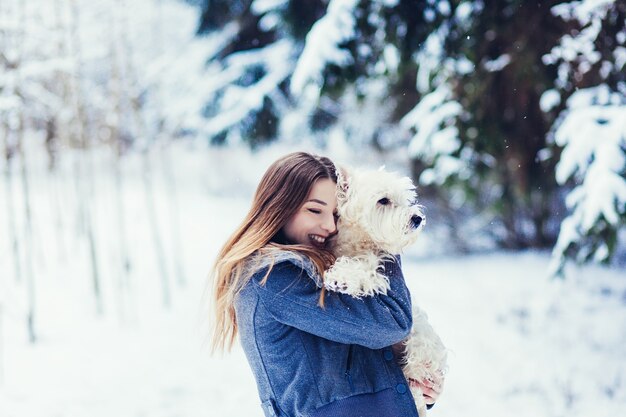 Glückliches Mädchen mit ihrem Hund, weißer Terrier im Freien im Winterpark