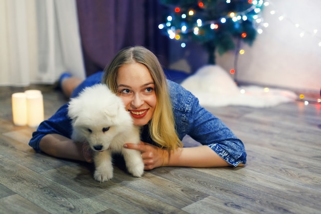 Glückliches Mädchen mit Samojede-Husky-Hund in Weihnachtsdekorationen