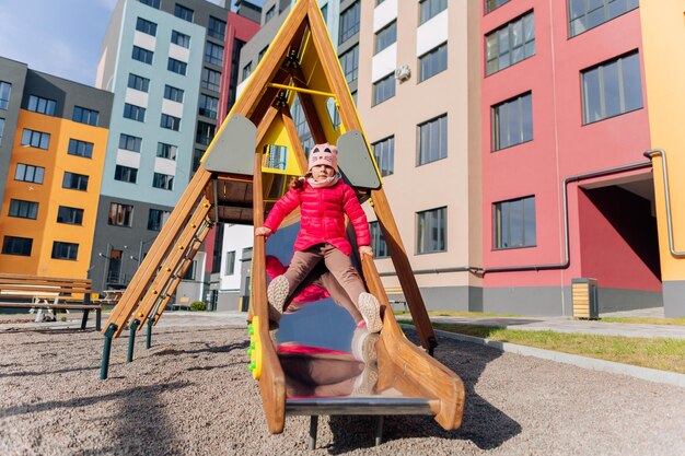 Glückliches Mädchen und Junge, die auf dem Rutschenmädchen auf dem Spielplatz spielen