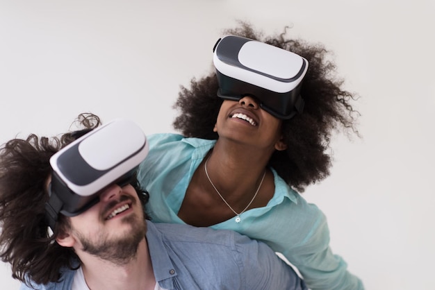 Glückliches multiethnisches Paar, das Erfahrungen mit VR-Headset-Brillen der virtuellen Realität macht, isoliert auf weißem Hintergrund