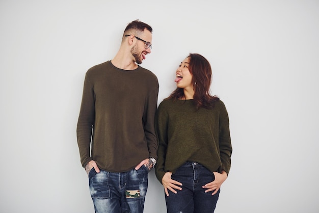 Glückliches multiethnisches Paar in Freizeitkleidung ist drinnen im Studio zusammen. Kaukasischer Typ mit asiatischer Freundin.