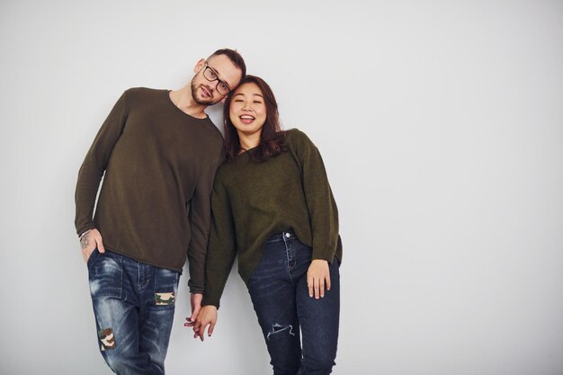 Glückliches multiethnisches Paar in Freizeitkleidung ist drinnen im Studio zusammen. Kaukasischer Typ mit asiatischer Freundin.