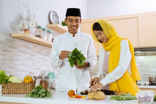 Glückliches muslimisches Paar, das zusammen in der Küche kocht. Mann und Frau bereiten sich auf das Abendessen vor