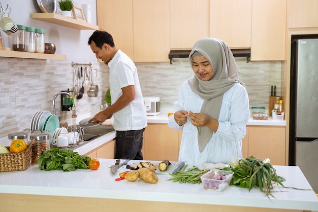 Glückliches muslimisches Paar, das zusammen in der Küche kocht. Mann und Frau bereiten sich auf das Abendessen vor