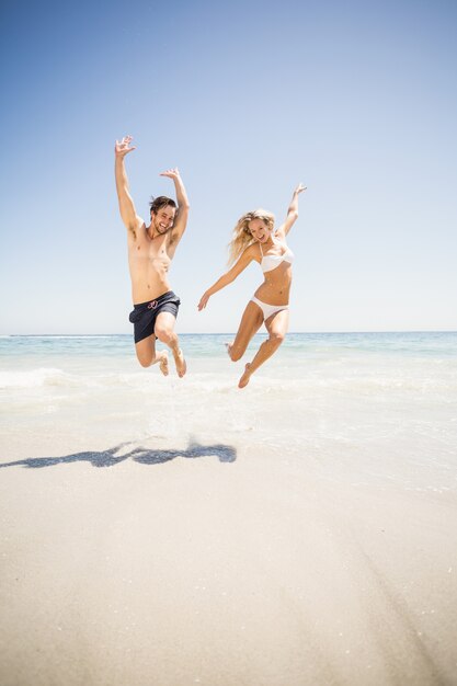 Glückliches Paar am Strand springen