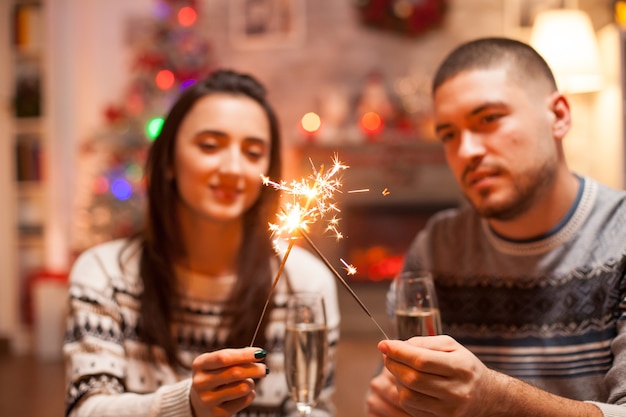 Glückliches Paar am Weihnachtstag mit Handfeuerwerk.