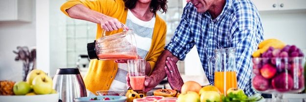 Glückliches Paar bereitet Smoothie in der Küche zu