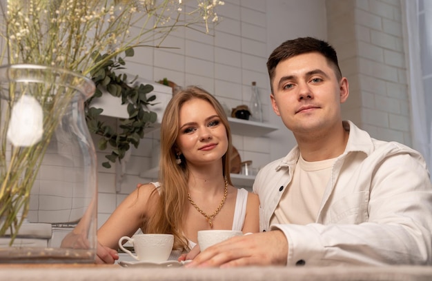 Glückliches Paar, das am Küchenporträt sitzt Schöne Frau und gutaussehender Mann trinken Tee oder Kaffee Zartes Beziehungskonzept
