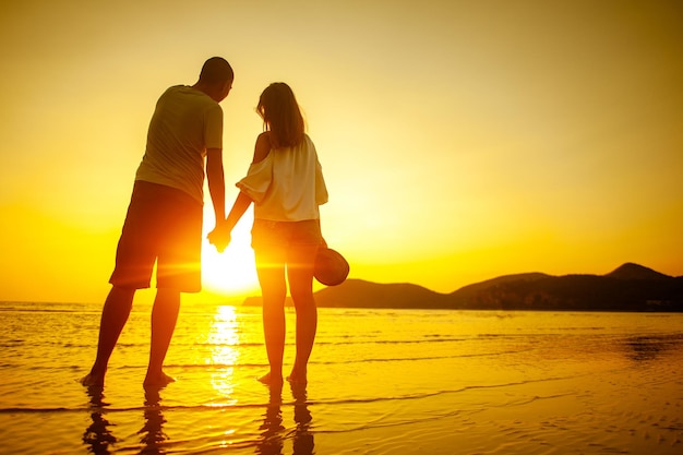 Glückliches Paar, das am Sonnenuntergangsstrand zum Meer läuft.