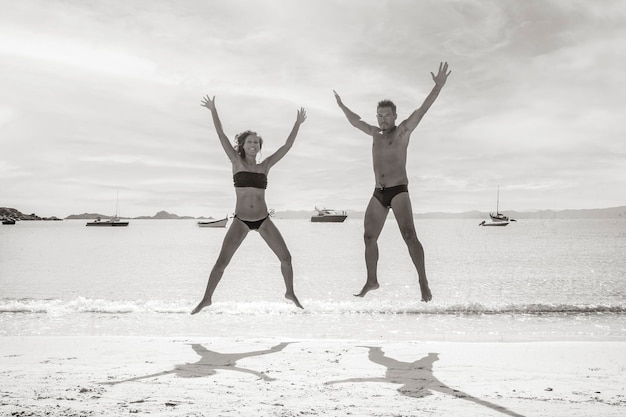 Glückliches Paar, das am tropischen Strand springt Reisekonzept mit verliebten Menschen auf der ganzen Welt