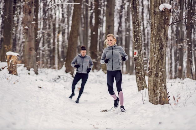 Glückliches Paar, das am verschneiten Wintertag in der Natur läuft. Spaß, gesundes Leben, Beziehung