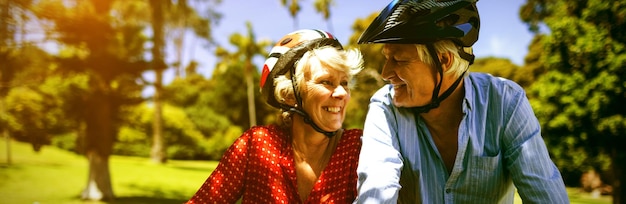 Glückliches Paar, das an einem sonnigen Tag im Park Fahrrad fährt