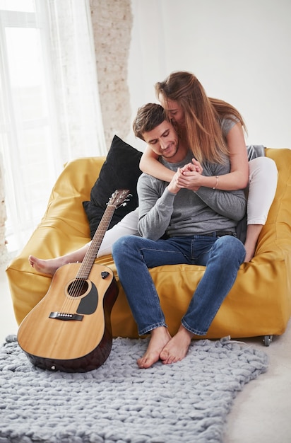 Glückliches paar, das auf dem gelben sofa im wohnzimmer ihres neuen hauses entspannt.