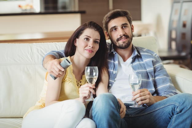 Glückliches Paar, das auf Sofa entspannt und Gläser Champagner hält