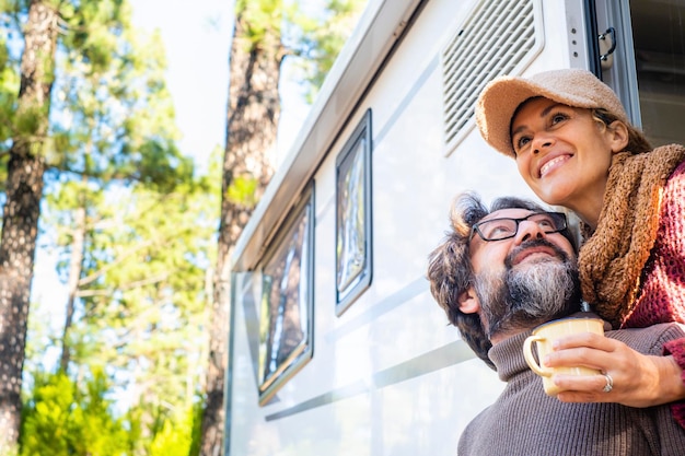 Glückliches Paar, das das Outdoor-Waldziel genießt und gemeinsam außerhalb seines Wohnmobilfahrzeugs lächelt Konzept des alternativen Reiseurlaubs und des freien netzunabhängigen Lebensstils Menschen, die mit Wohnmobil reisen