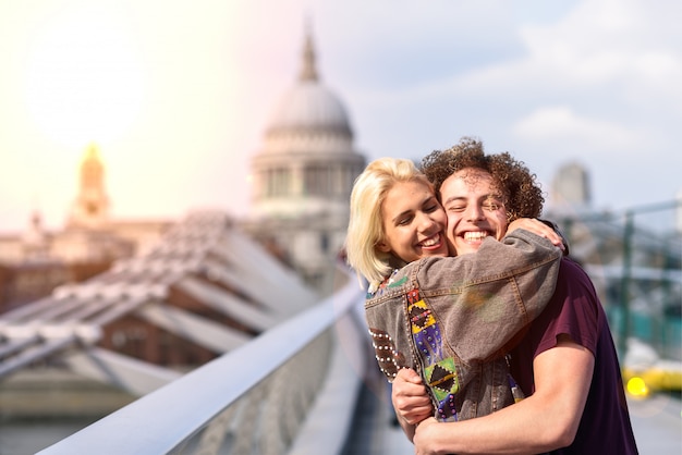 Glückliches Paar, das durch Jahrtausendbrücke, die Themse, London umarmt.
