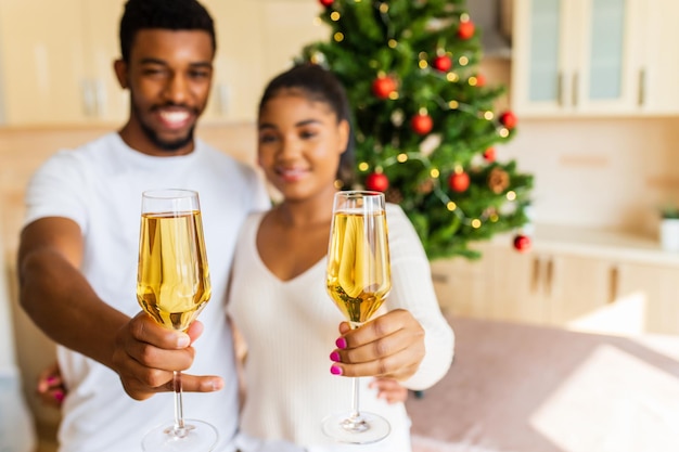 Glückliches Paar, das ein Glas Champagner hält und das neue Jahr zu Hause feiert