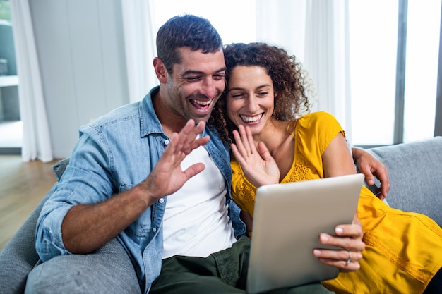 Glückliches Paar, das eine digitale Tablette auf Sofa verwendet