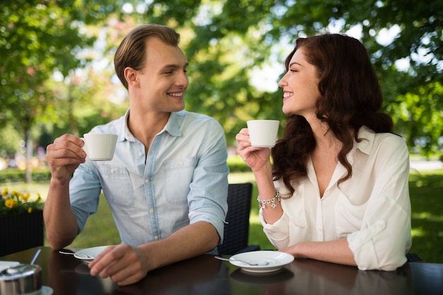 Glückliches Paar, das einen Cappuccino beim draußen sitzen trinkt