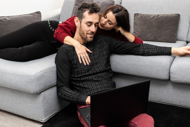 Glückliches Paar, das einen Laptop in ihrem Haus benutzt