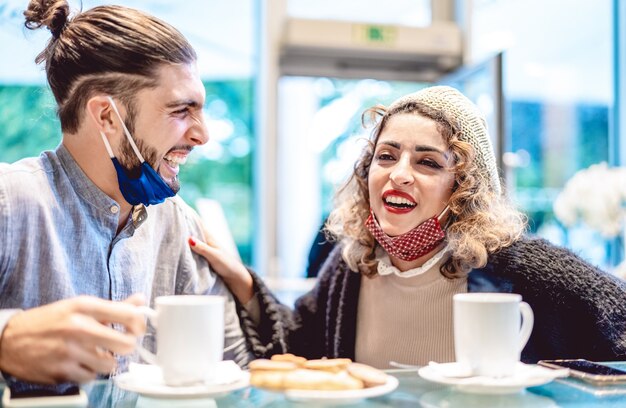 Foto glückliches paar, das gesichtsmaske trägt, die spaß zusammen in der bar-cafeteria hat