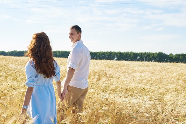 Glückliches Paar, das Hände hält, die durch eine Wiese gehen. Das Konzept von Liebe, guten Beziehungen, Verständnis und Harmonie.