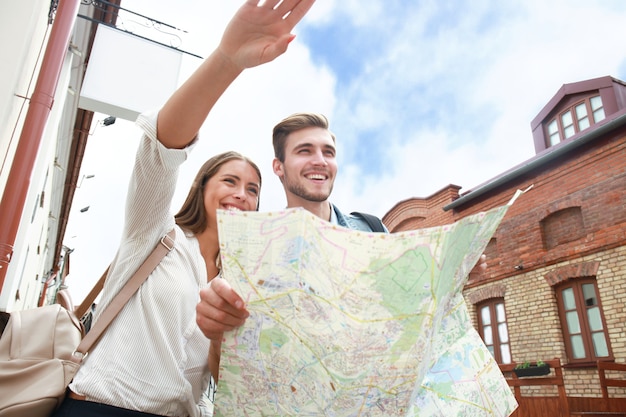 Glückliches Paar, das im Freien Sightseeing macht und eine Karte hält.