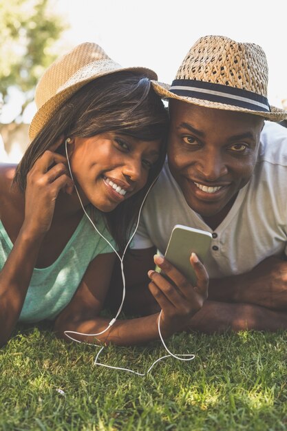 Glückliches Paar, das im Garten zusammen hört Musik liegt