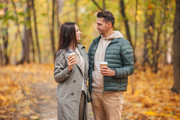 Glückliches Paar, das im Herbstpark an einem sonnigen Herbsttag geht