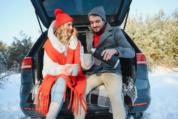 Glückliches Paar, das im offenen Auto sitzt und einen Zwischenstopp einlegt Romantisches Reisekonzept Winterwald