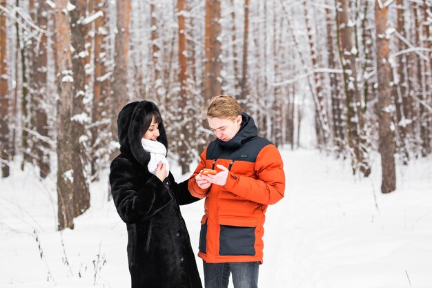 Glückliches Paar, das im Winter auf der Straße ein Smartphone berät