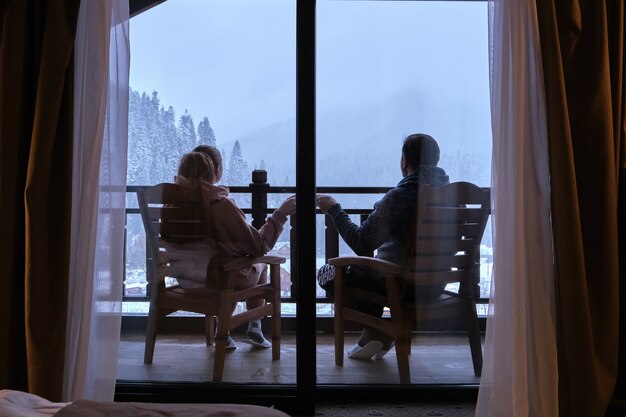 Glückliches Paar, das Kaffee auf dem Balkon eines Berghotels mit einem schönen Blick auf die Berge trinkt