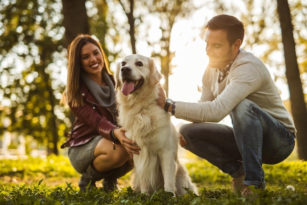 Glückliches Paar, das mit einem Hund im Park spielt