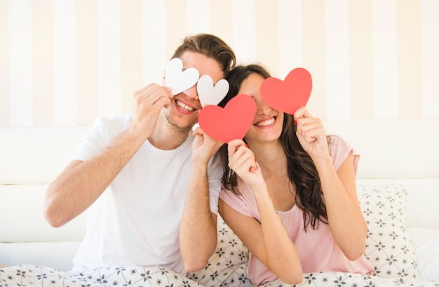 Foto glückliches paar, das mit papierherzen aufwirft