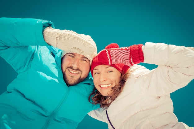 Glückliches Paar, das sich im Winter im Freien vor blauem Himmelshintergrund amüsiert