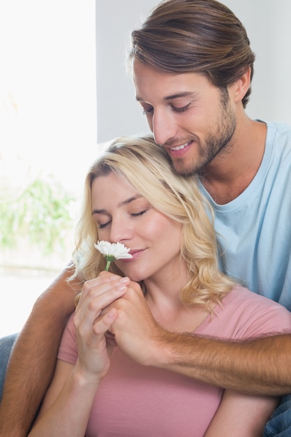 Glückliches Paar, das sich zusammen auf der Couch mit riechender Blume des Mädchens entspannt