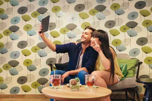 Glückliches Paar, das Social Media in einem Notizbuch an der Bar aufpasst. mach ein Foto