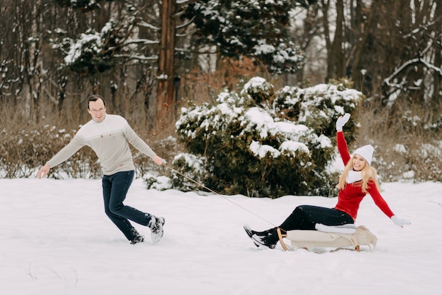 Glückliches Paar, das Spaß draußen im Schneepark hat.