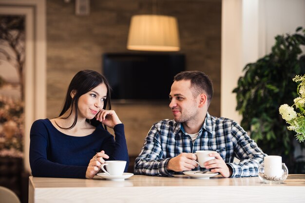 Glückliches Paar, das Tee und Kaffee im Café trinkt