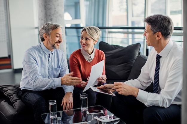 Glückliches Paar, das während des Treffens mit seinem Finanzberater über Papierkram spricht