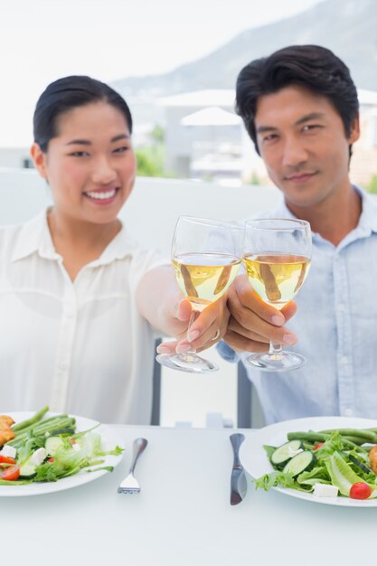 Glückliches Paar, das Weißwein mit einer Mahlzeit isst